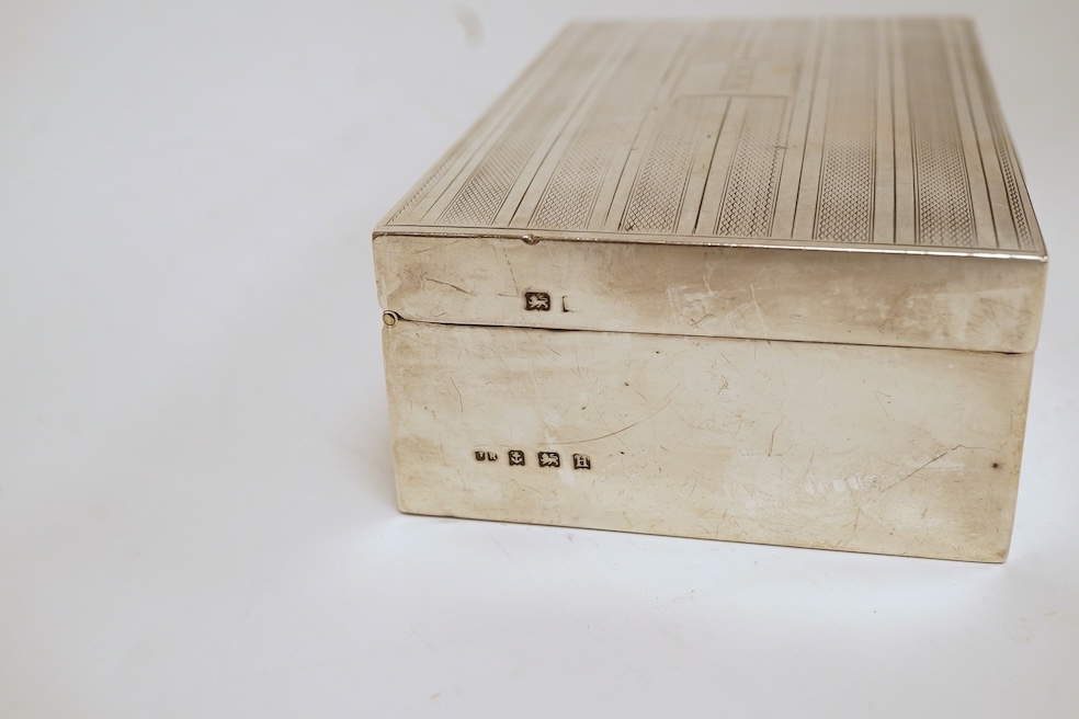 A George V silver mounted rectangular cigarette box, with later engraved inscription, Birmingham, 1932, 13.7cm, together with a similar silver vesta case and two modern silver wine labels. Condition - poor to fair